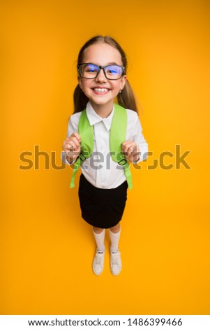 Happy School Days. Joyful Nerdy Schoolgirl In Eyewear Smiling At Camera Over Yellow Background In Studio. High-Angle Shot