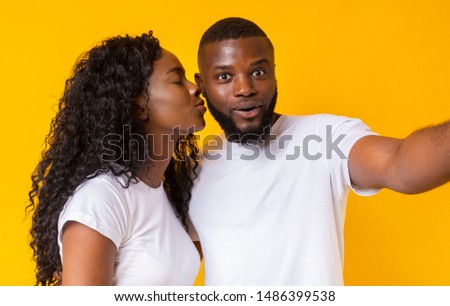 First kiss. African american couple in love taking selfie on yellow studio background