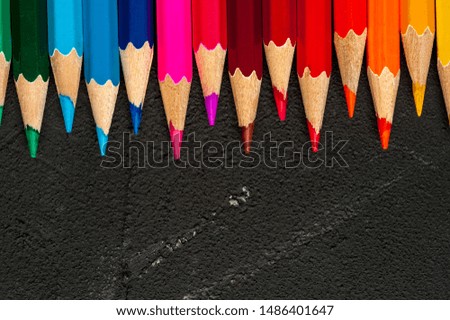 Close-up of multicolored sharpened pencils lie on each other on the table of an artist or a child. The concept of creativity and drawing