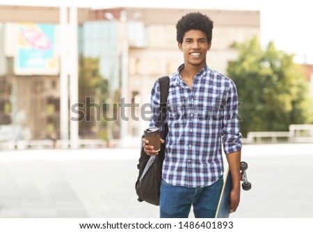 Attractive young african guy walking in the city drinking takeaway coffee, copy space