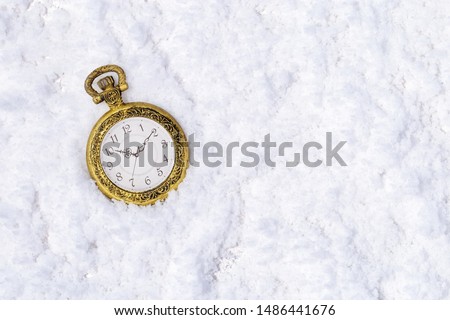 Vintage glod clock (pocket watch) on snow. New Year 2020 background or greeting card with copy space.  Top view. 