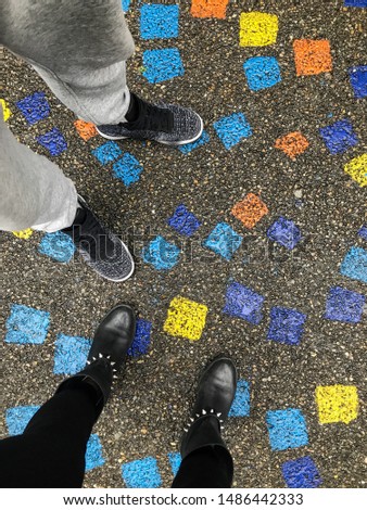 Photograph of male and female legs on an asphalt street with various colorful Sticky Notes