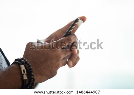 Close up image african american mans hands holding smartphone, isolated on white background. Electronic device user texting message, doing online website purchases, browsing internet, playing game.