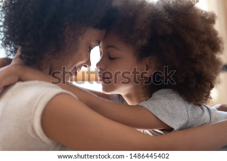 Close up head shot side view calm happy mixed race mother cuddling little cute daughter, touching foreheads. Tender moment family support, forgive and understanding. Adopted kid hugging foster mom. Royalty-Free Stock Photo #1486445402