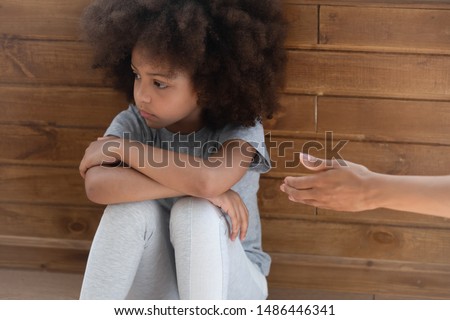 Upset african american little adorable kid girl ignoring lent mommys hand. Offended unhappy mixed race child suffering from quarrel, does not want to forgive, feeling stressed and misunderstood. Royalty-Free Stock Photo #1486446341