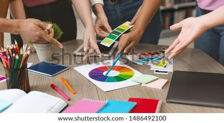 Young creative graphic designers choosing color swatch samples for selection coloring, working with new project, close up