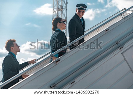 Smiling crew of aiplane going up to plane board stock photo. Airways concept