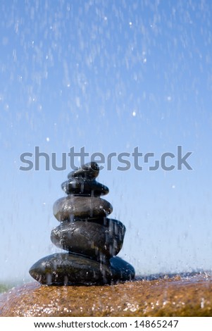 Pyramid from stones under a rain in beams of the sun on a background of the sky