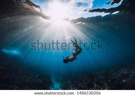 Free diver woman with fins over coral bottom and amazing sun rays. Freediving underwater in ocean Royalty-Free Stock Photo #1486530206
