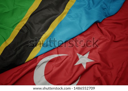 waving colorful flag of turkey and national flag of tanzania. macro