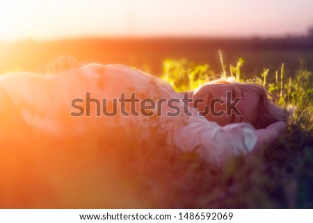 Beautiful young woman laying in grass in sunlight