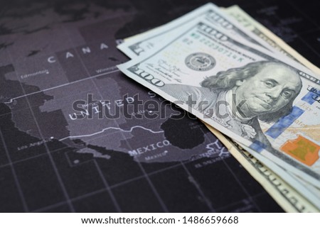 US dollar banknotes on world  map, black gray background with white letter. Closed-up banknotes and United. Economic of USA concept. Stock market of USA. Economy USA. Business crisis. Stimulus check 
