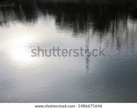 Reflections in water. Abstraction. Beautiful and magical reflection in the water of the sky and trees. Background of trees mirrored on rippled water surface 