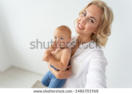 family and motherhood concept - happy young blond mother with little baby taking selfie
