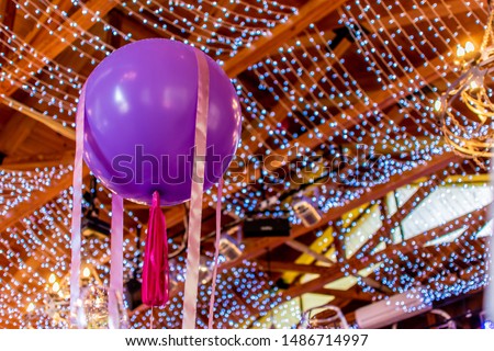 Large round colored balloon close up with a festive ribbon. birthday, celebration. Decorated with garlands ceiling dining