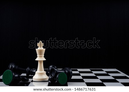 Chess king standing wins the game of chess setup on dark background. Chess concept save the king and save the strategy, game over.
