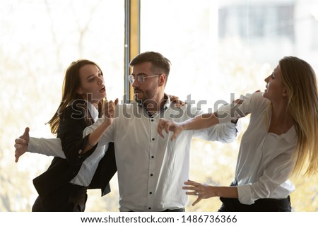 Male colleague set apart two envious jealous aggressive business women coworkers fighting at corporate office meeting, angry female rivals have bad relation competition conflict violence at workplace Royalty-Free Stock Photo #1486736366