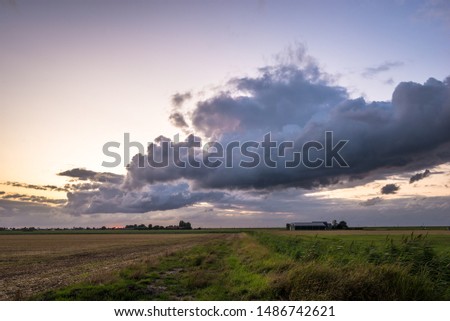 Beautiful clouds over the flat, wide open dutch landscape at dusk
