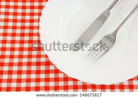 Fork and knife in plate on red tablecloth