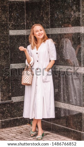 Young happy girl in a white dress in green sandals with pearls.