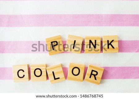 words pink color written in cubic letters on a pink striped textiles background, selective focus.