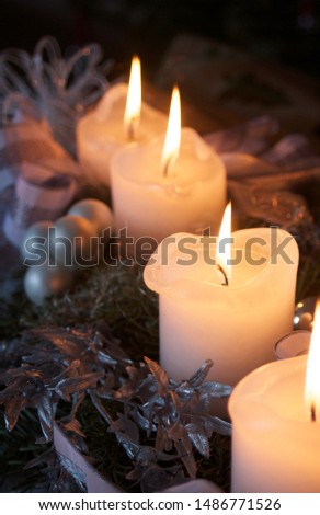 Arrangement with 4 white candles and all with flame, warming white