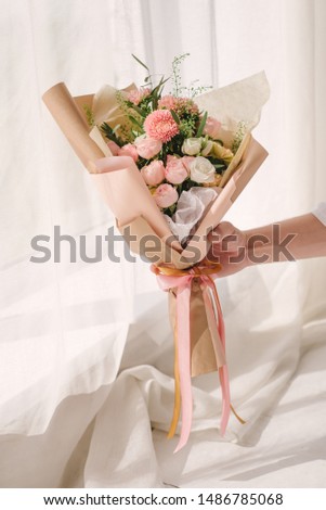 Very beautiful florist woman holding a beautiful colorful blooming bouquet of flowers on a gray wall background. Toning