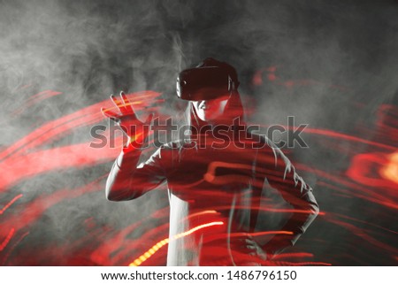 girl uses virtual reality helmet, concept of modern technology, effect of double exposure. Young woman playing VR games, fire special effects and computer graphics on the background of a gray image