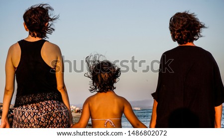 Grandmother, mother and daughter walking on sand. Three different generation conceptual picture.