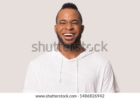 Excited african American young man in glasses and sport clothes isolated on grey background laugh looking ta camera, smiling black millennial male in casual wear and spectacles feel happy overjoyed