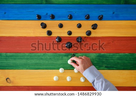 Top view of male black and white chess pieces positioned in pyramid shape opposite to each other. Over colorful wooden background.