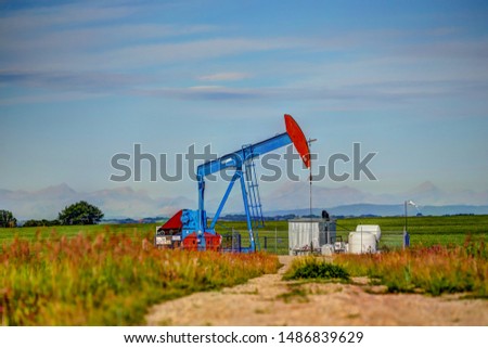 Crude oil pump jack set against the Rocky Mountains in rural Alberta