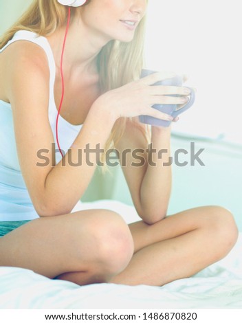 Portrait of beautiful woman in morning listening music sitting on bed at home. Portrait of beautiful woman