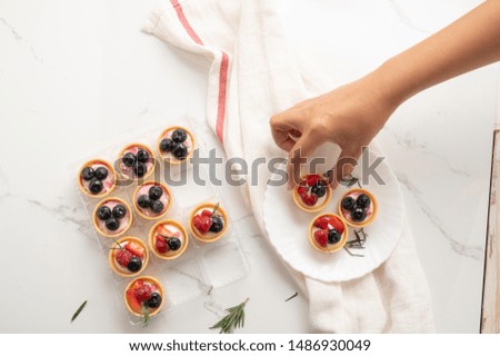 Top view hand of woman holding mix berry fruits pie cake,Food concept background