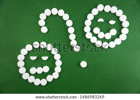 emoticons from white pills on a green background               