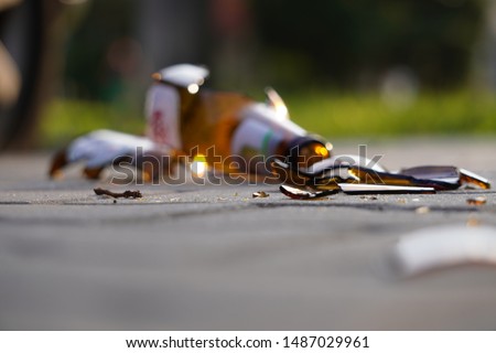 bottle of beer, soda or drugs from dark glass is broken. Shattered beer bottle on ground in sunset light. Fragments of glass on asphalt. Texture, background, wallpaper. Royalty-Free Stock Photo #1487029961