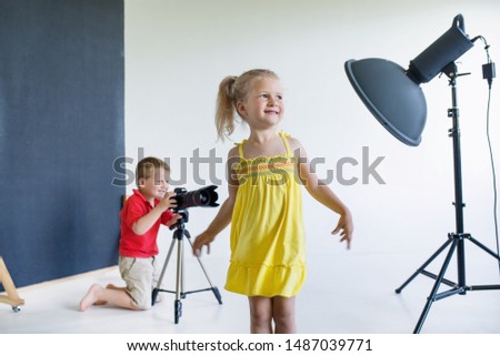 Little boy and girl play in photographer and model in profession