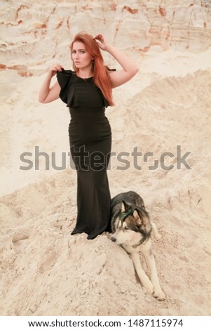 Funny best friends concept. Happy young female person walks in the desert with big dog malamute outdoors