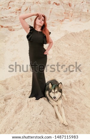 Funny best friends concept. Happy young female person walks in the desert with big dog malamute outdoors