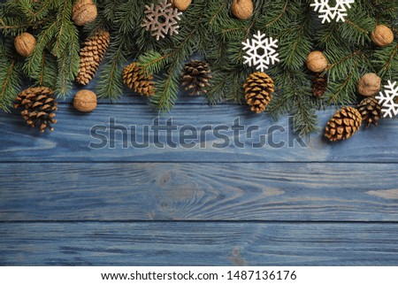 Fir branches with Christmas decoration on blue wooden background, flat lay. Space for text