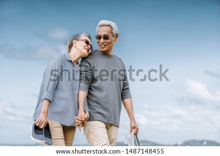 Asian senior couple or elderly people walking and siting at the beach on their weekend vacation holiday. Retirement vaction concept. Royalty-Free Stock Photo #1487148455