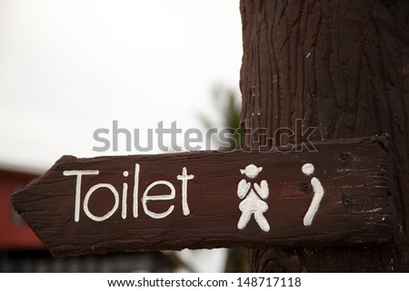 toilet plate sign on wooden pole
