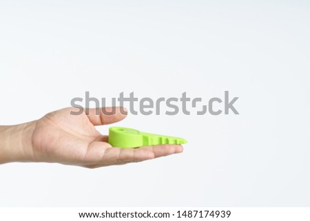Hand holding big plastic or rubber key for door stop on white background