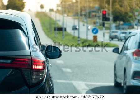 Luxury of black car stop on the asphalt junction by traffic light control in across. Traveling in the provinces during the bright period. with open light brake.