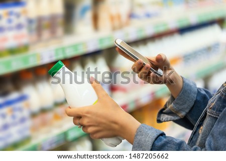 Buyer photographs a bottle of milk, a mystery shopper. Checking the quality of the goods by barcode, closeup
