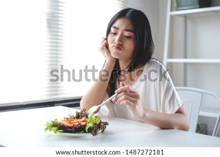 The girl has a boring expression when she eats vegetables. She wants to eat delicious food. Diet, Clean food, Healthy food concept.
 Royalty-Free Stock Photo #1487272181