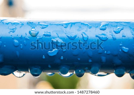 Raindrops on a blue metal pipe.