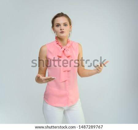 Photo studio portrait of a cute young woman girl in a beautiful suit of white-pink tender color on a white background. He stands right in front of the camera, explains with emotion.