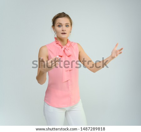 Photo studio portrait of a cute young woman girl in a beautiful suit of white-pink tender color on a white background. He stands right in front of the camera, explains with emotion.