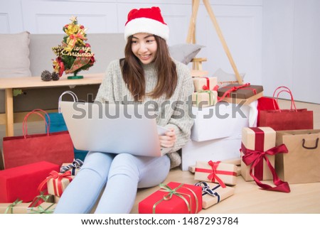 Woman is holding credit card and doing shopping online near Christmas tree at home.